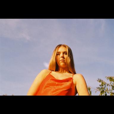 aiyana in an orange top against the blue sky