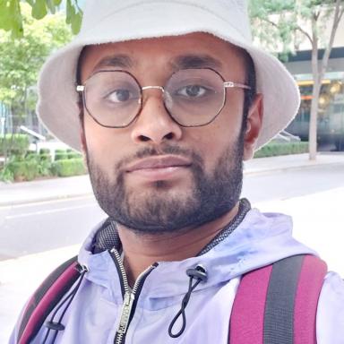 Manoj wearing a light coloured bucket hat and glasses 