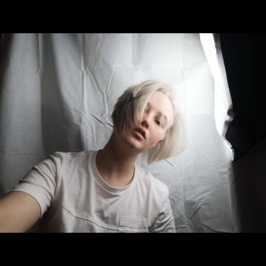 Angharad wearing a white t-shirt in front of a white fabric background