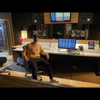 Daniel in a recording studio, wearing a yellow hoody and black cap