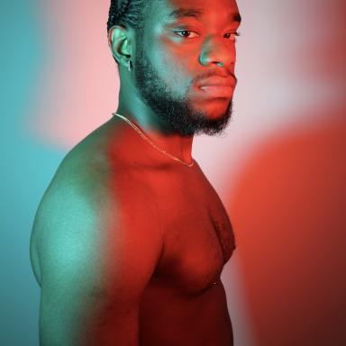 Mirari shirtless lit by red and blue lights