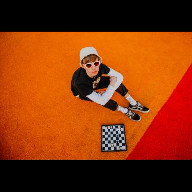 Lemonade Shoelace from above, sitting on orange and red carpet with a chessboard