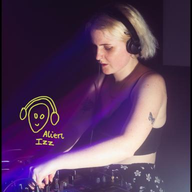 alien izz wears black headphones while DJing