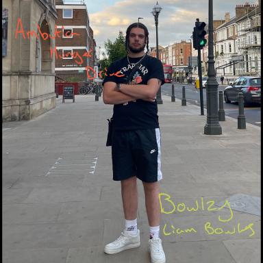 bowlzy stands in the street with his arms folded