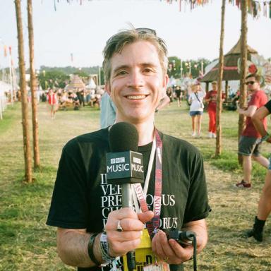 mark savage holds a BBC Music microphone at a festival