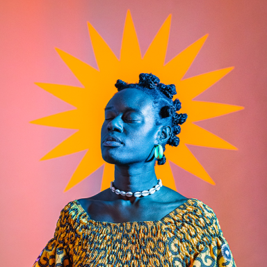 marla kether closes her eyes. her hair is in bantu knots and an orange shape is behind her like a star aura.