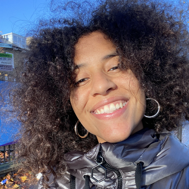 a woman with an afro smiles in a puffa jacket