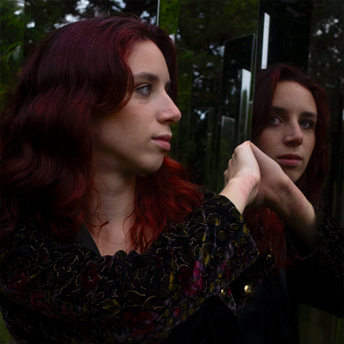 a woman with red hair turns to the side and looks in the mirror