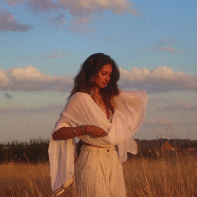 a woman stands in a field and wears a white dress
