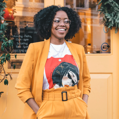 a woman smiles and wears a yellow suit