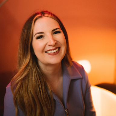 a woman with auburn hair and red lipstick smiles at the camera