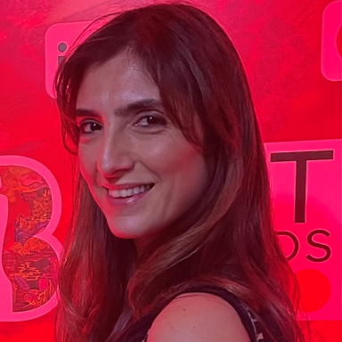 a woman with brown hair looks over her shoulder and smiles