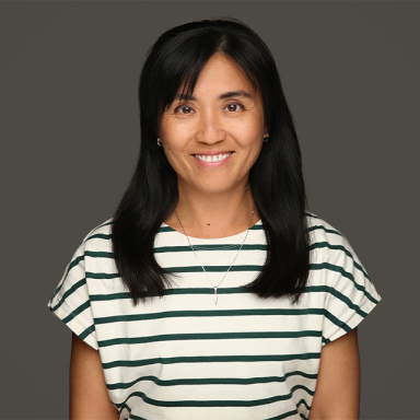 a woman with dark hair wears a stripy top and smiles