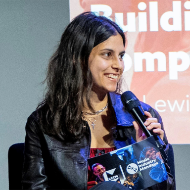 talia holds a microphone and looks to the crowd whilst on a panel