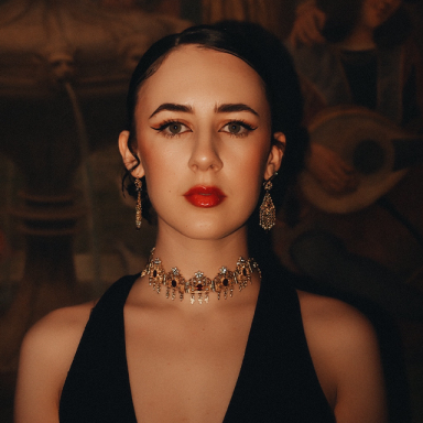 a woman with a black halterneck top, red lipstick and choker necklace has brown hair tucked behind her ears